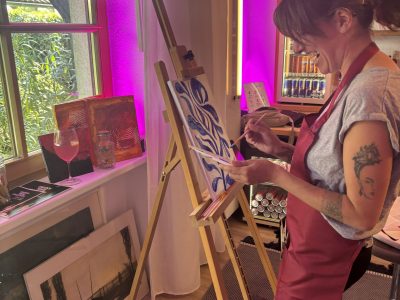 Paint and Drink Event von Ländle Event. Frau an der Staffelei am Malen.